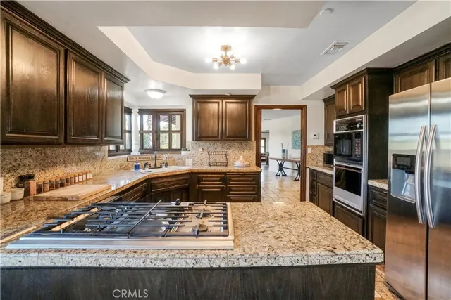 a kitchen with stainless steel appliances granite countertop a stove a sink and a refrigerator