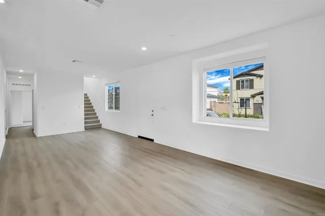 a view of an empty room with window and wooden floor