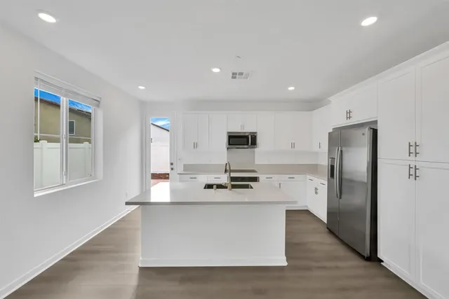 a large kitchen with stainless steel appliances a large counter top and a refrigerator