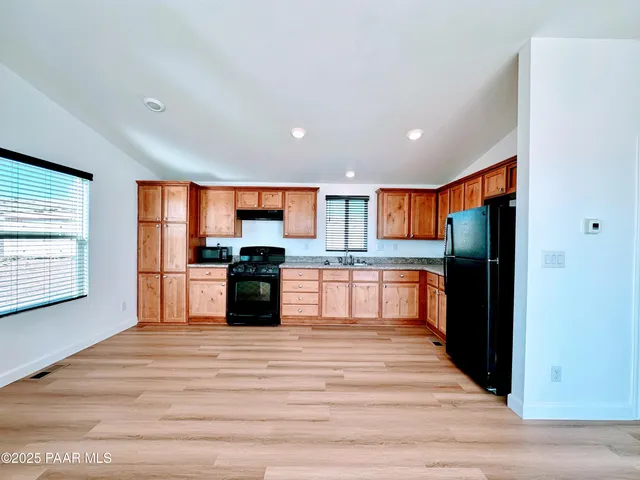 a kitchen with stainless steel appliances kitchen island granite countertop a refrigerator and wooden cabinets