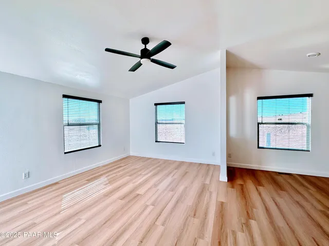 a view of empty room with wooden floor and window