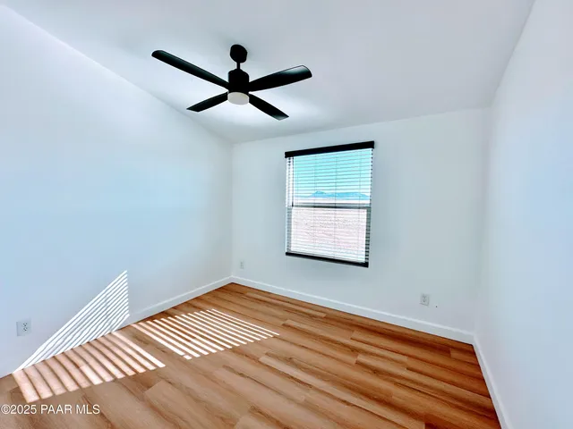 a view of a room with wooden floor and a ceiling fan