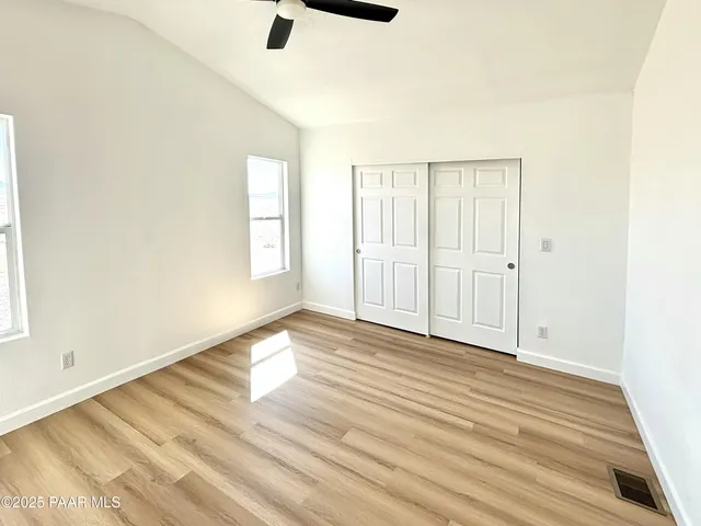 an empty room with wooden floor cabinet and windows