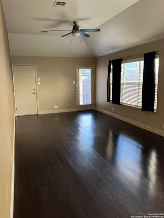 a view of an empty room with wooden floor and a window
