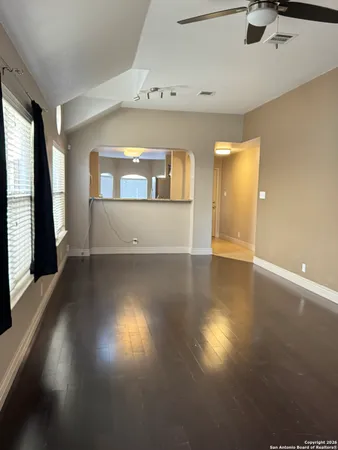 an empty room with wooden floor and windows