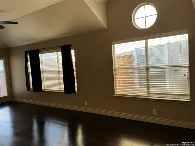 a view of an empty room with wooden floor and a window