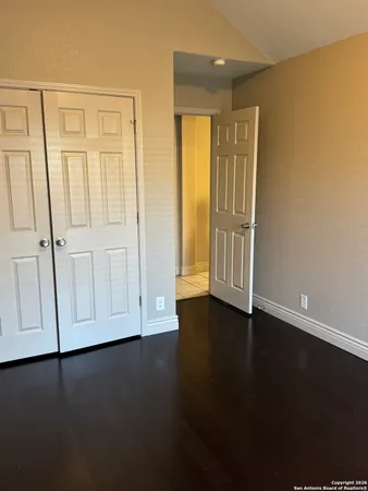 an empty room with wooden floor and windows with curtains