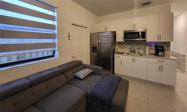 a kitchen with stainless steel appliances a sink a stove a microwave a refrigerator and cabinets