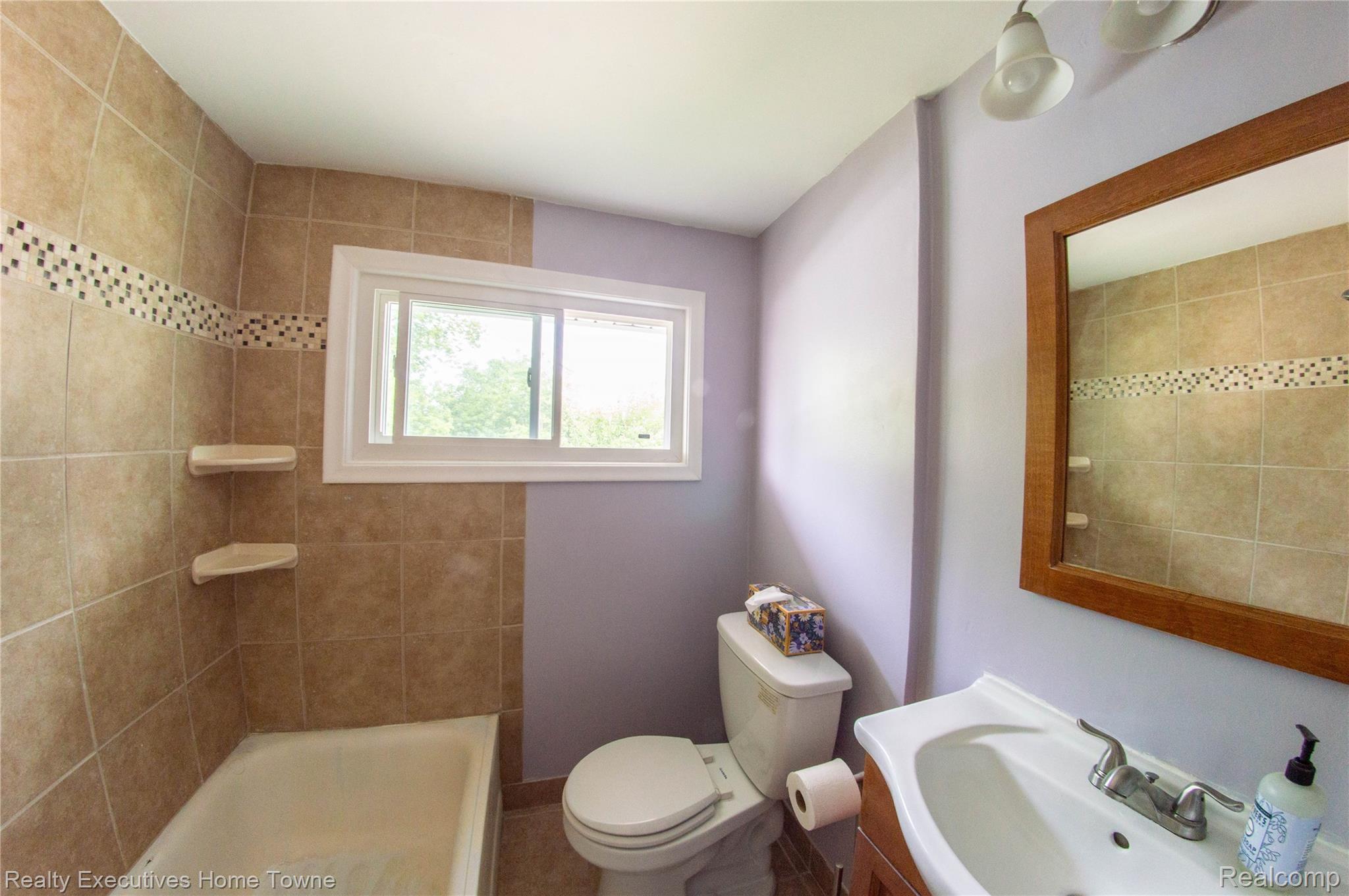 2676 Cumberland Road Berkley, MI 48072 - Photo 24 of 38 Bathroom featuring a tiled shower surround with decorative mosaic accent, a sliding window, and a wood-framed mirror