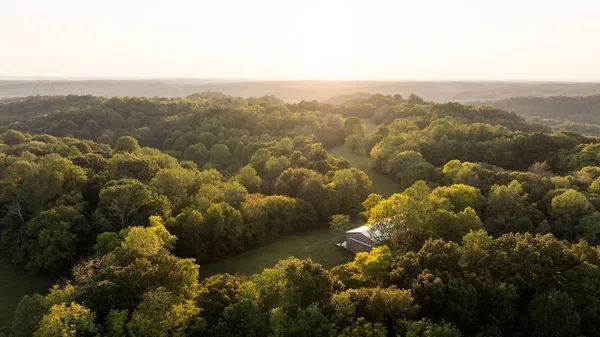 a aerial view of a house next to a yard and large trees