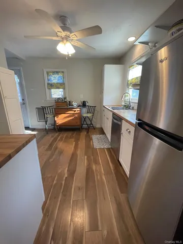 a view of entryway with kitchen island wooden floor and electronic appliances