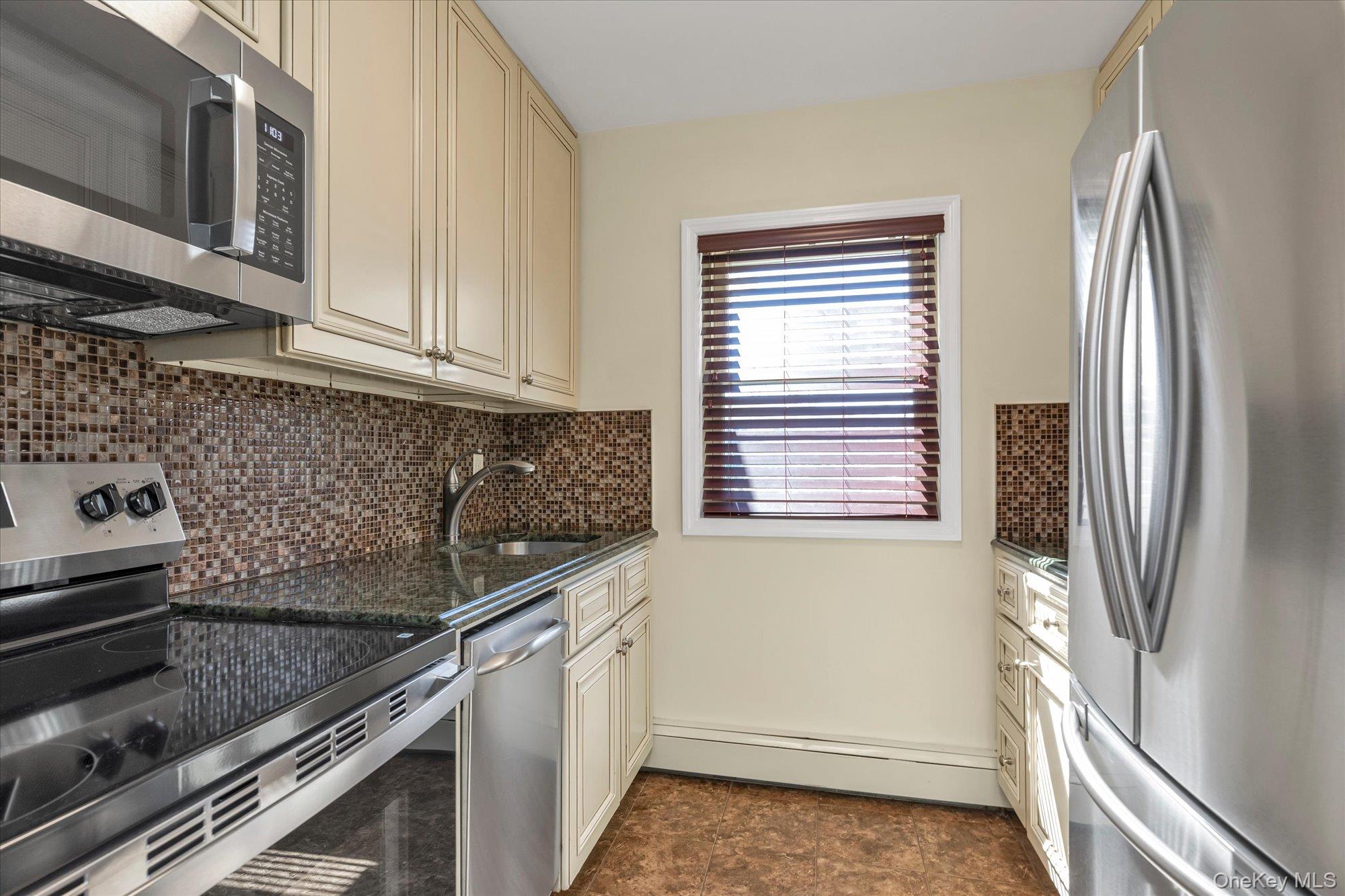4 Rose Street, Unit 5H1 Oceanside, NY 11572 - Photo 7 of 18 a kitchen with granite countertop a refrigerator and a stove
