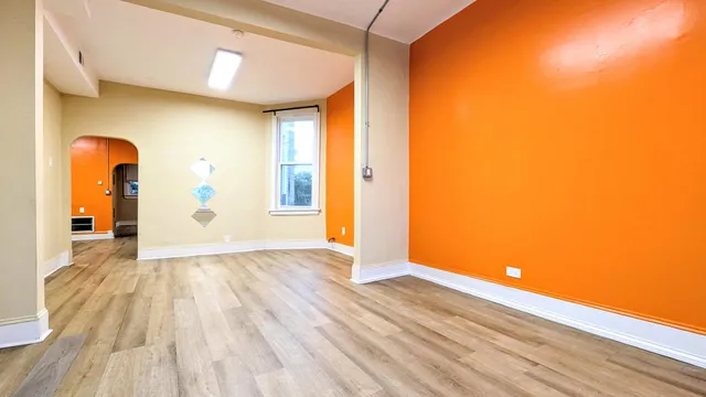 a view of an empty room with wooden floor and a window