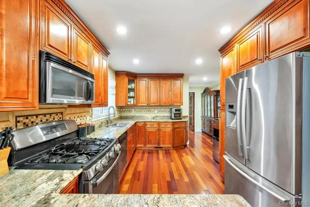 a kitchen with wooden floor a large window and stainless steel appliances