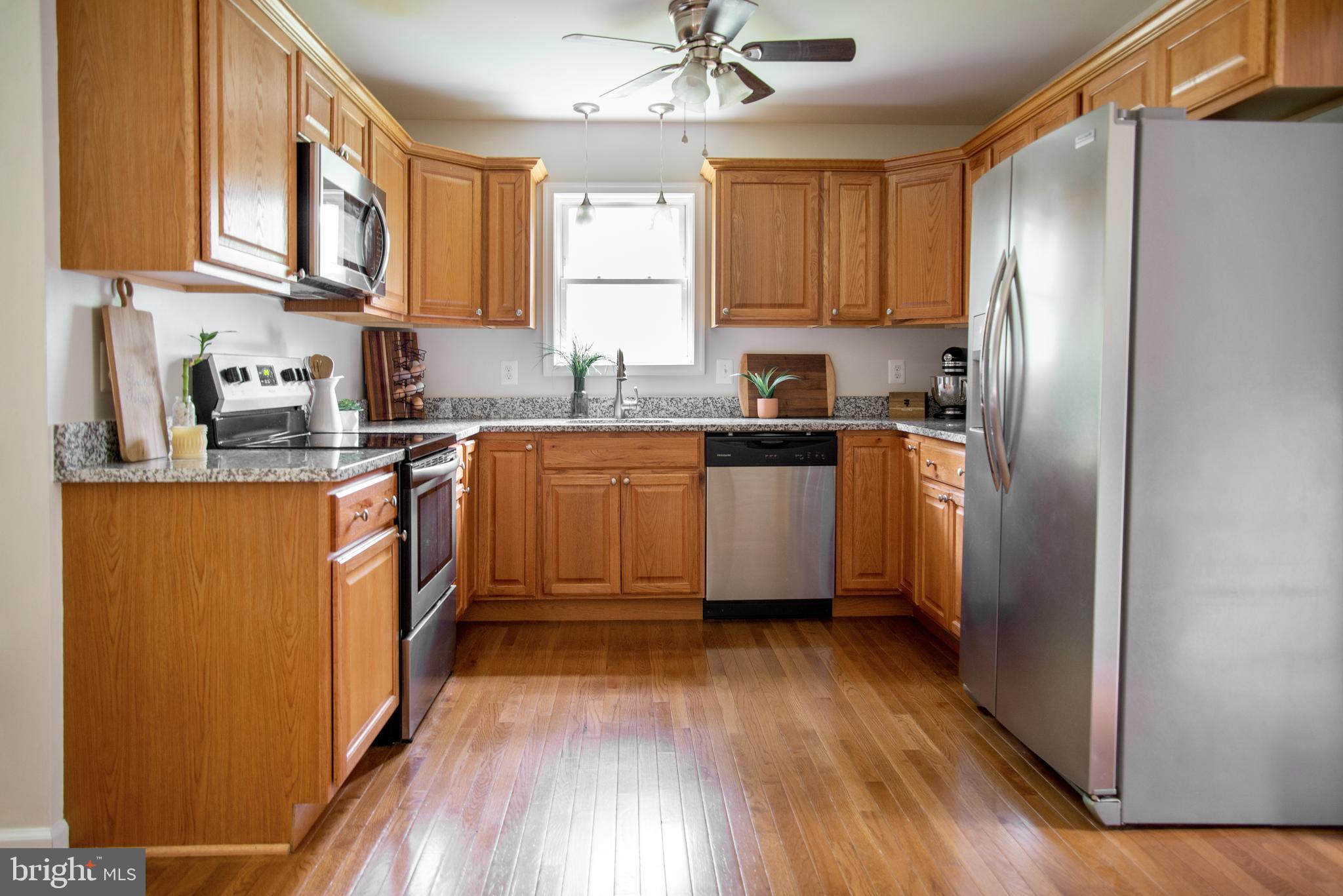 5588 Courtneys Corner Road Sumerduck, VA 22742 - Photo 7 of 22 a kitchen with stainless steel appliances granite countertop wooden cabinets a refrigerator a sink a stove a microwave and wooden floors