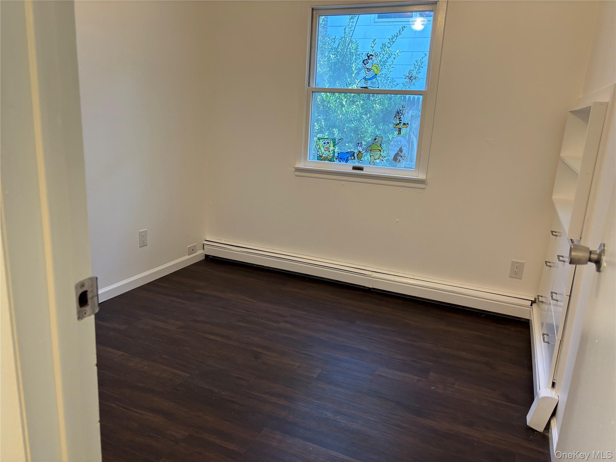 679 A Meadow Road Smithtown, NY 11787 - Photo 11 of 30 Empty room with dark wood-style floors, baseboard heating, and a baseboard heating unit