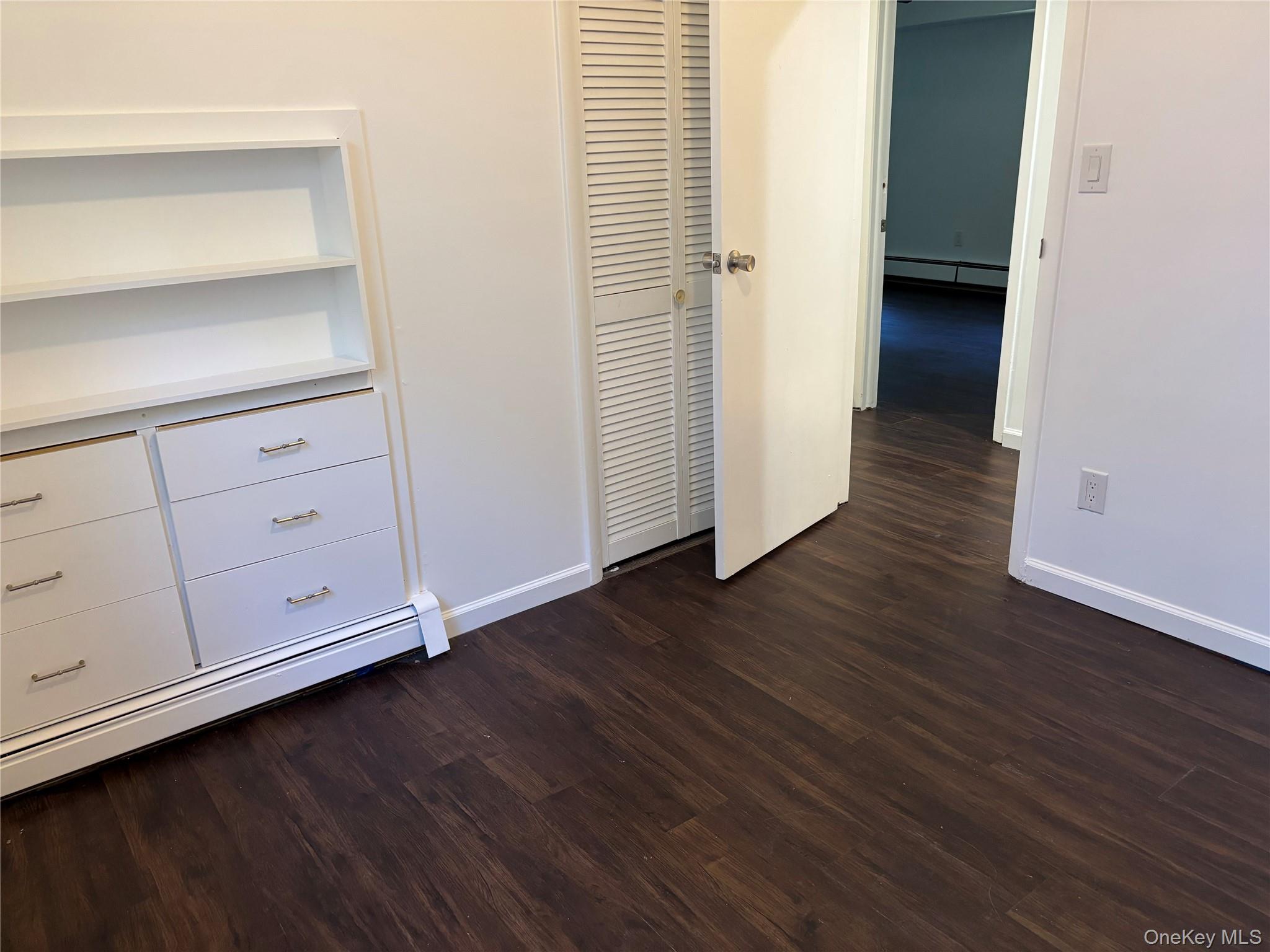 679 A Meadow Road Smithtown, NY 11787 - Photo 12 of 30 Unfurnished bedroom featuring dark wood-style flooring and a baseboard heating unit