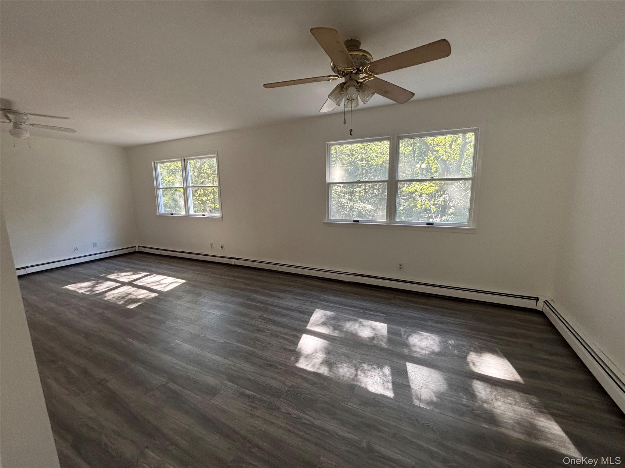 679 A Meadow Road Smithtown, NY 11787 - Photo 18 of 30 Spare room with ceiling fan, dark wood-style flooring, and baseboard heating