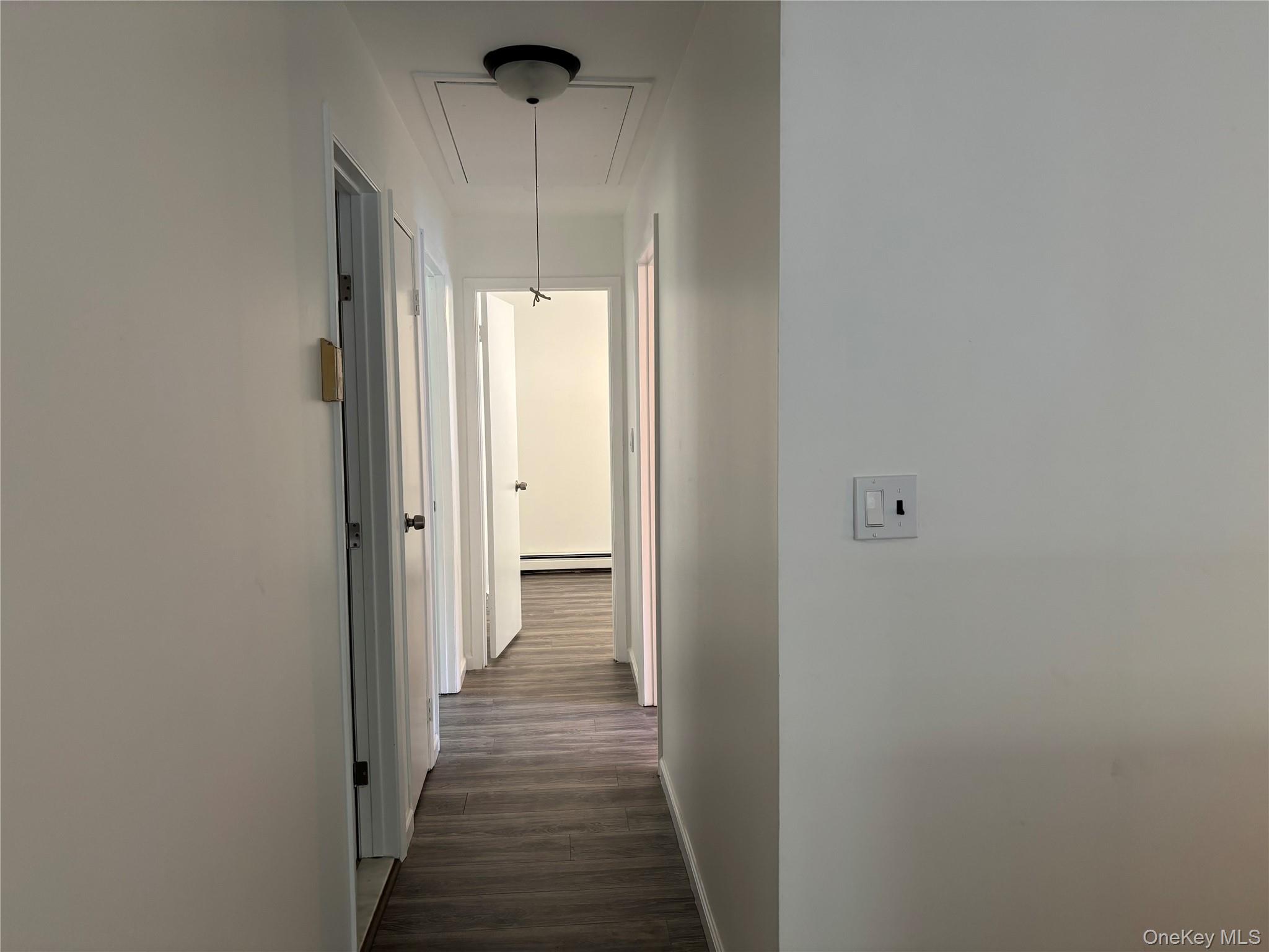 679 A Meadow Road Smithtown, NY 11787 - Photo 21 of 30 Corridor with attic access, dark wood finished floors, and a baseboard radiator