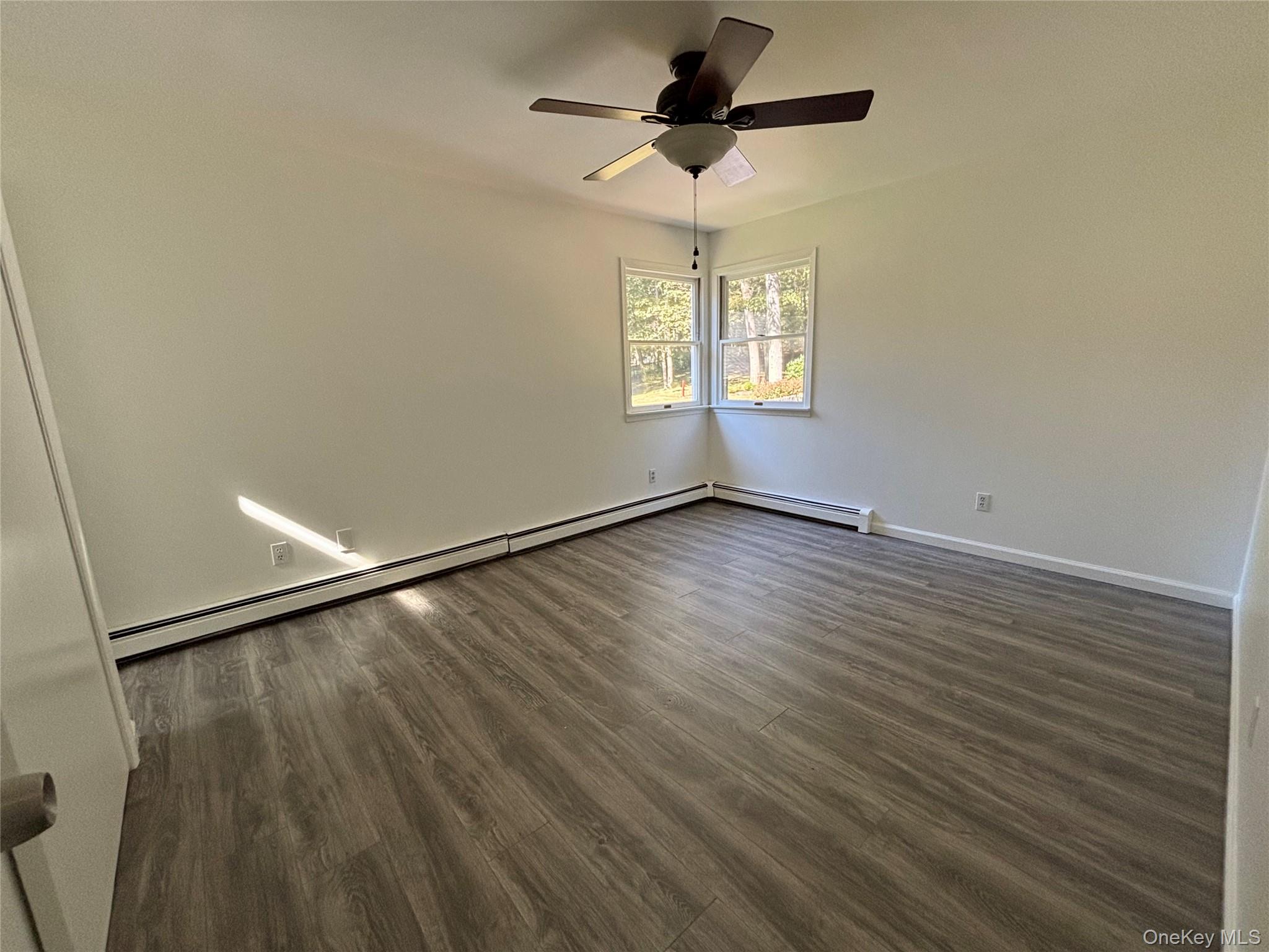 679 A Meadow Road Smithtown, NY 11787 - Photo 22 of 30 Spare room with dark wood-style floors, a baseboard heating unit, and a ceiling fan