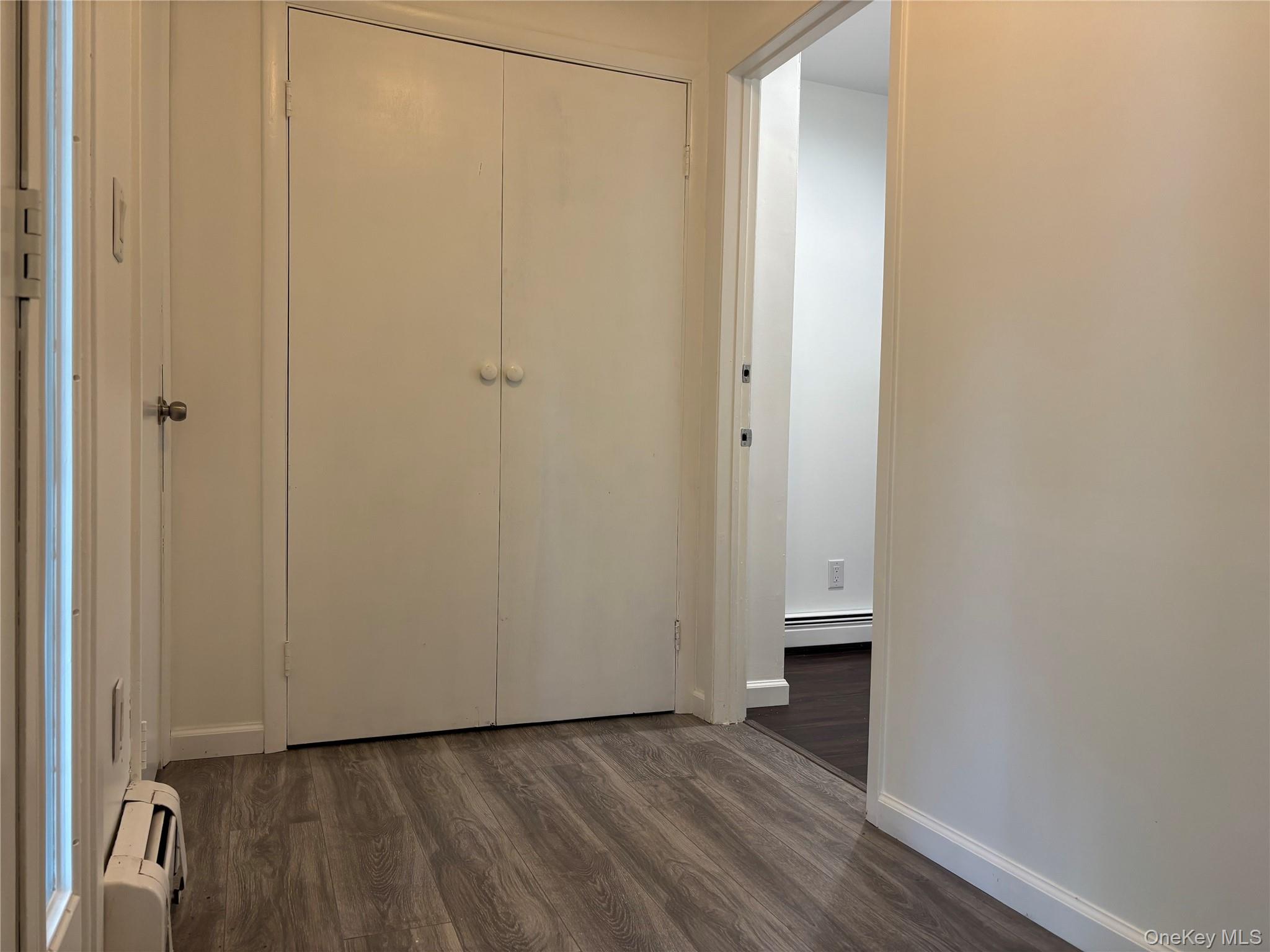 679 A Meadow Road Smithtown, NY 11787 - Photo 3 of 30 Unfurnished bedroom featuring dark wood-style floors, baseboard heating, and a closet