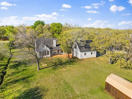 an aerial view of residential houses with outdoor space and trees