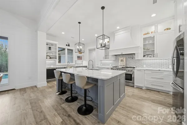a kitchen with kitchen island stainless steel appliances a table chairs sink and stove top oven