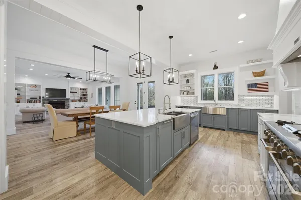 a large kitchen with stainless steel appliances kitchen island granite countertop a large counter top a stove a sink and a wooden floors