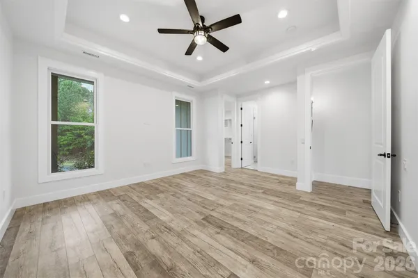 a view of empty room with wooden floor and fan