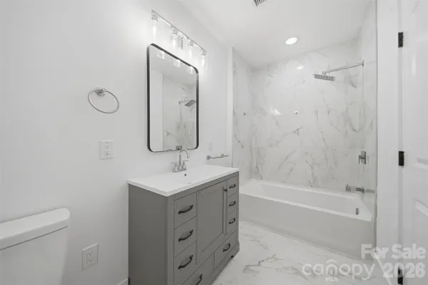 a bathroom with a granite countertop sink a toilet and shower