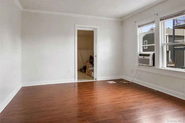 a view of an empty room with wooden floor and windows