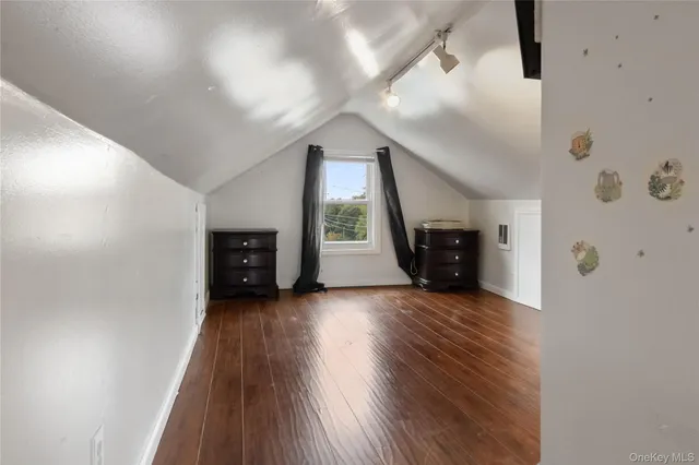 an empty room with wooden floor fireplace and windows