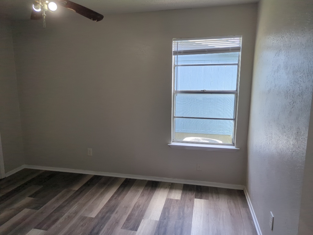 512 Lenora Drive, Unit B Taylor, TX 76574 - Photo 10 of 11 a view of an empty room with wooden floor and a window