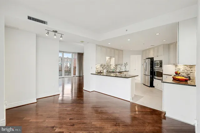 a large white kitchen with white cabinets and stainless steel appliances