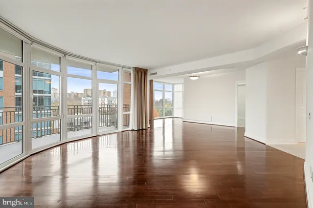 a view of empty room with wooden floor and floor to ceiling window