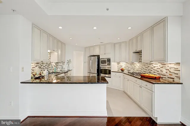 a large kitchen with stainless steel appliances kitchen island granite countertop a refrigerator and a stove top oven