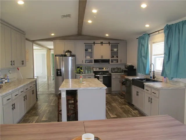 a large kitchen with stainless steel appliances granite countertop a stove refrigerator and cabinets