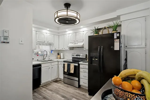 a kitchen with stainless steel appliances granite countertop a sink a stove a refrigerator and cabinets