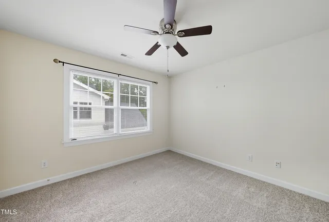 an empty room with a window and a fan