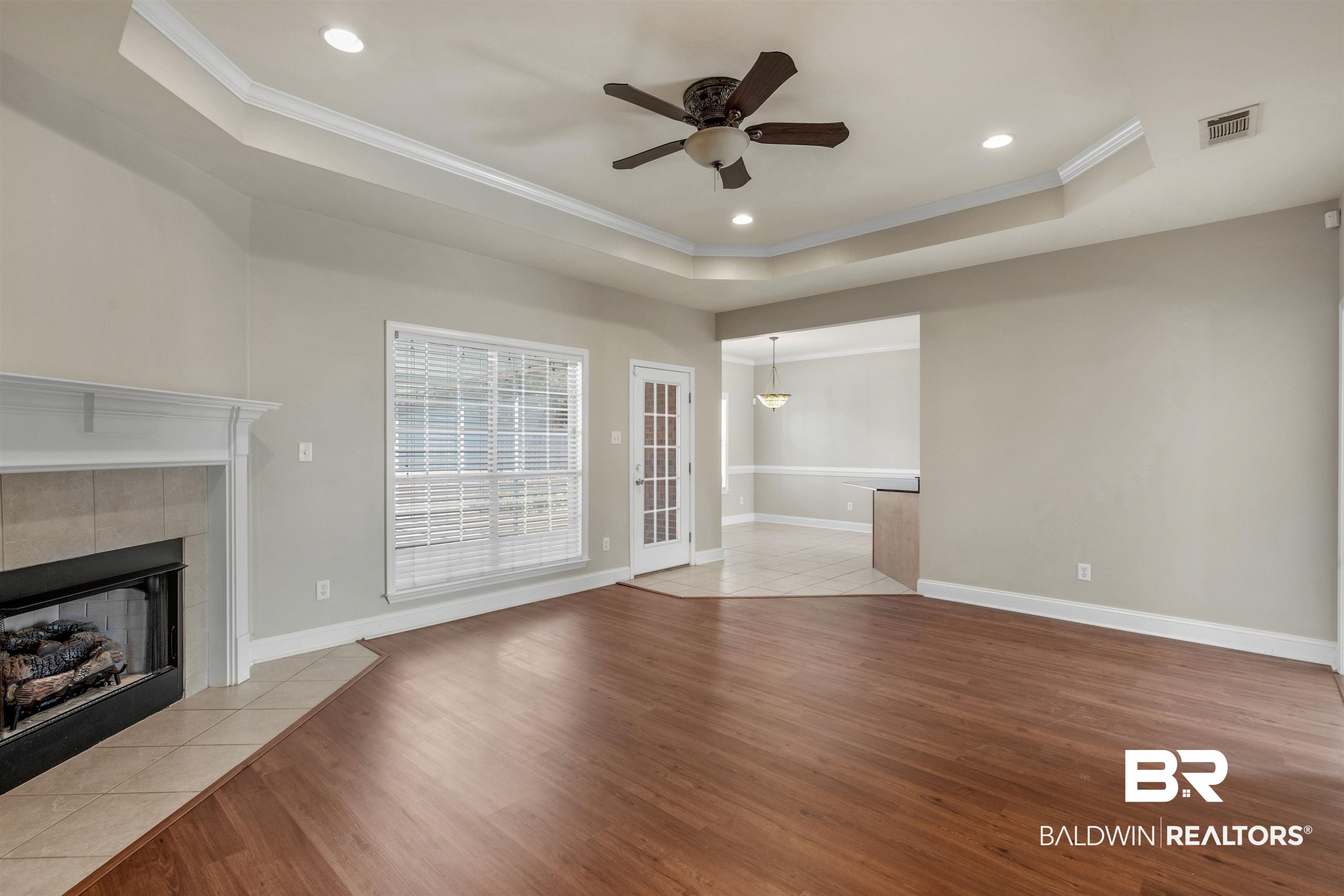330 Allison Court Mobile, AL 36608 - Photo 6 of 27 Unfurnished living room with a tile fireplace, ceiling fan, a raised ceiling, crown molding, and light hardwood / wood-style flooring
