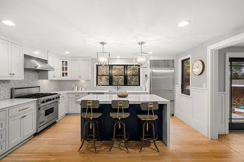a kitchen with stainless steel appliances kitchen island granite countertop a table chairs sink and cabinets