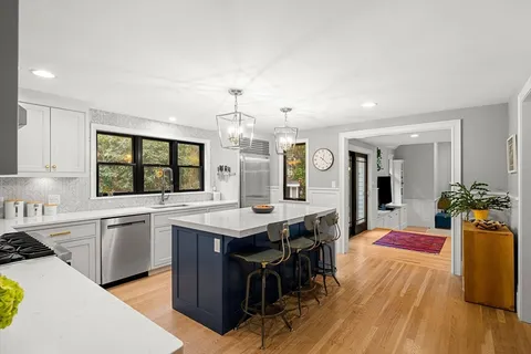 a kitchen with stainless steel appliances granite countertop a stove and chairs