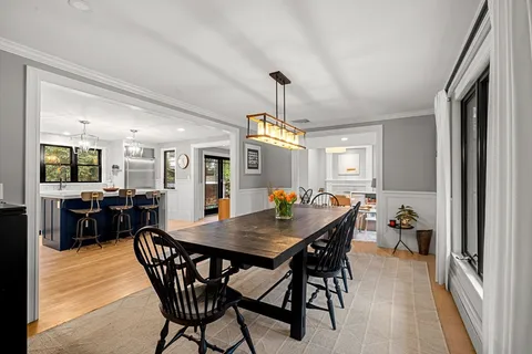 a view of a dining room and livingroom with furniture wooden floor a chandelier