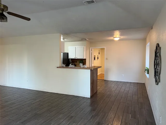 a view of a kitchen with a refrigerator and wooden floor