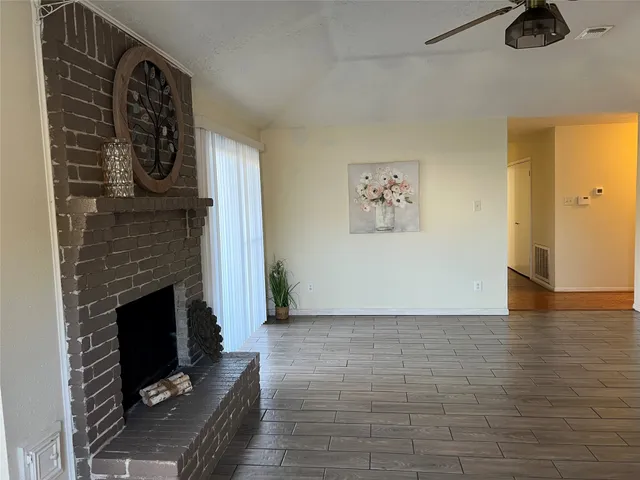 a view of an empty room with windows and fireplace