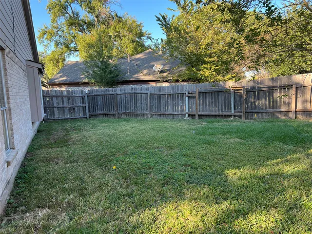a view of a yard with wooden fence and a trees