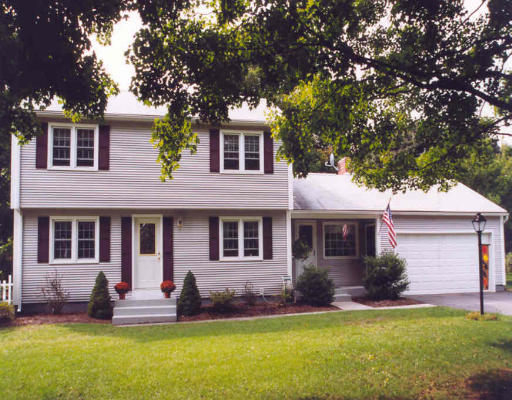 a front view of a house with a yard and tree