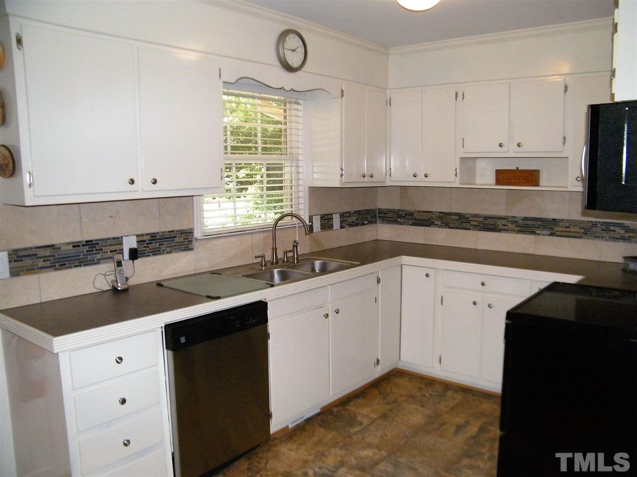 1302 Kingston Ridge Road Cary, NC 27511 - Photo 8 of 25 a kitchen with a sink dishwasher a stove and cabinets