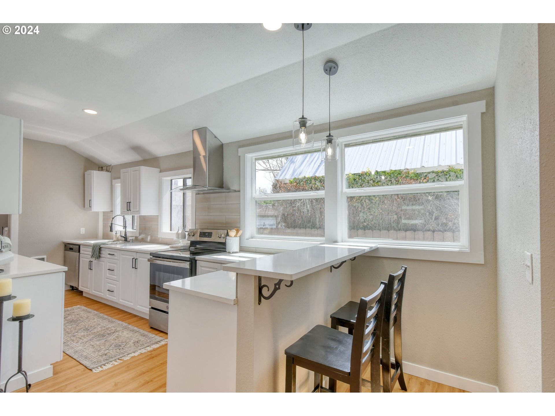 220 Southwest 4th Street Pendleton, OR 97801 - Photo 10 of 30 a kitchen with stainless steel appliances granite countertop a stove top oven a sink dishwasher and white cabinets with wooden floor