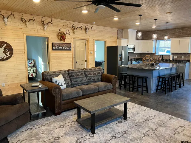 a living room with furniture a wooden floor and kitchen view
